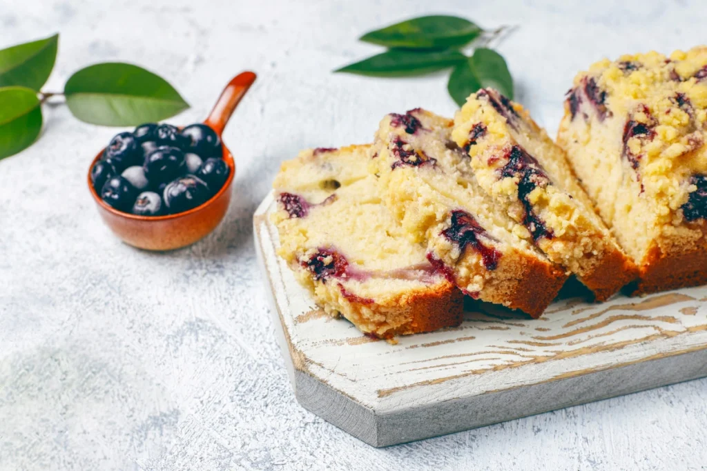 Rustic blueberry muffin tops with visible blueberries, dusted with sugar, on a wooden table