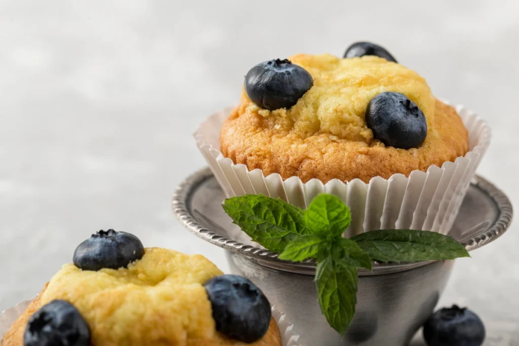 Rustic blueberry muffin tops with visible blueberries, dusted with sugar, on a wooden table."