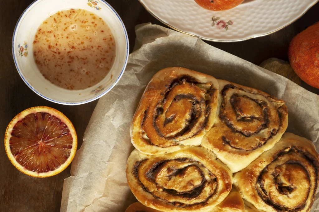 "Freshly baked cinnamon roll apple pie with whipped cream, caramel drizzle, apple slices, and a cup of coffee or apple cider on a cozy wooden table."